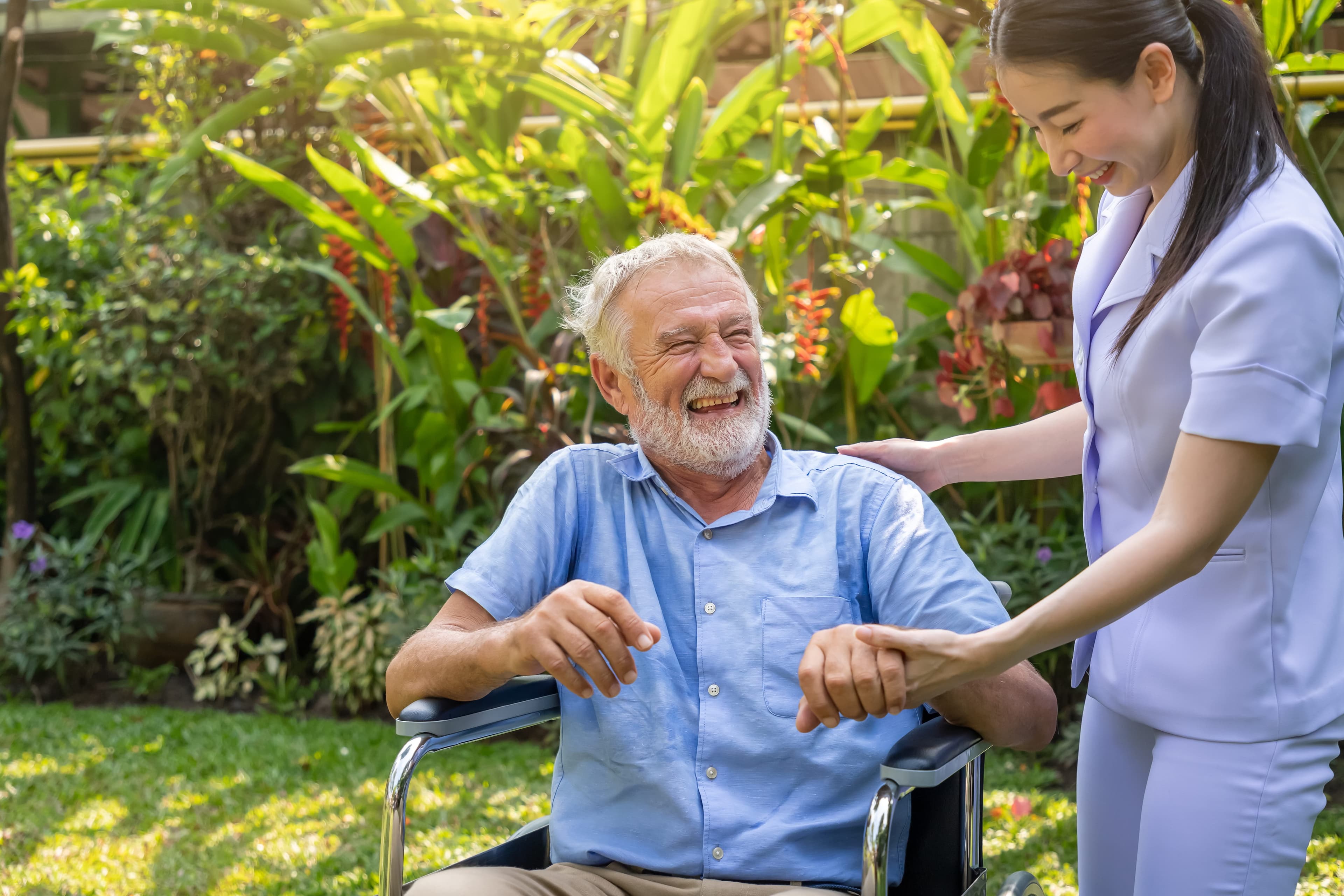 A nurse smiling while caring for an elderly patient at home